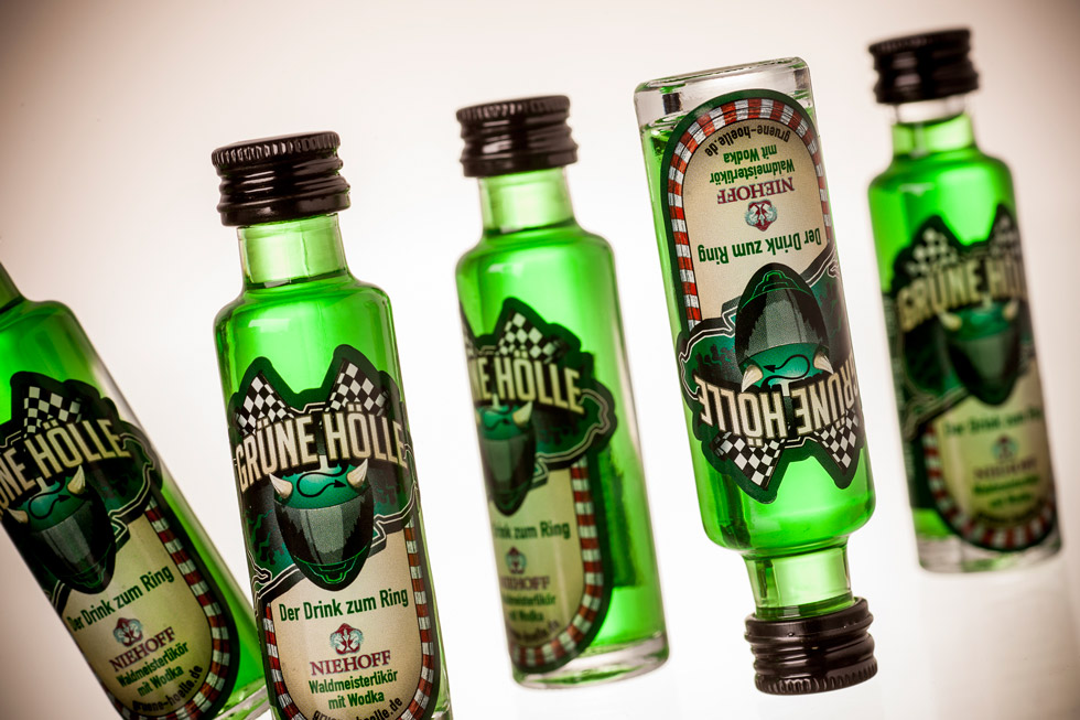Glasflaschen mit grüner Flüssigkeit und Aufkleber mit Grüne Hölle Logo.