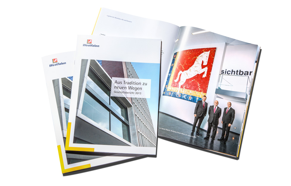 3 Geschäftsberichte der Westfalen AG. 2 zeigen das Cover und eine ist aufgeschlagen un zeigt ein weiteres Foto mit dem Vorstand.