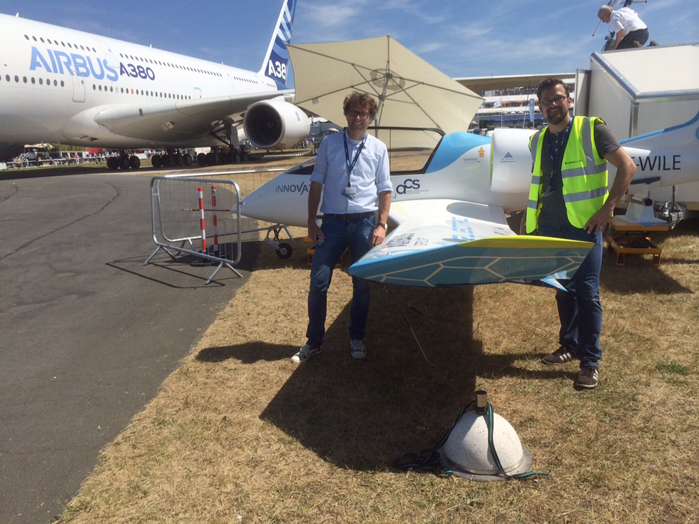 Sven und Tim Marquardt stehen auf einem Flugplatz neben einem E-Fan Flugzeug und schauen in die Kamera.