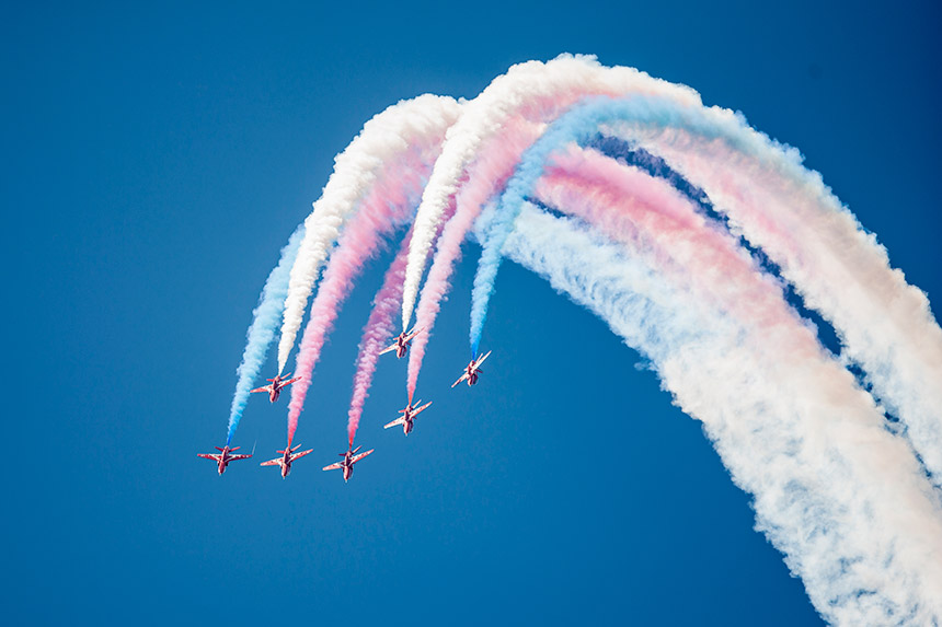 Red Arrows fliegen in Formation mit bunten Gas am Himmel.
