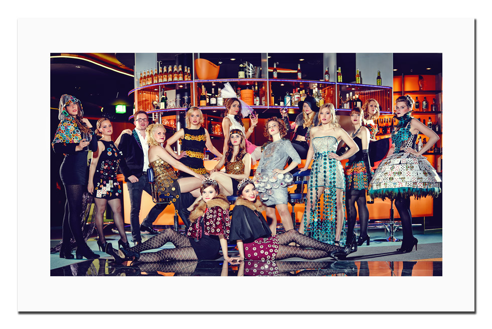 Ein Gruppenfoto vor einer Theke. AllePersonen tragen Kleidung, die mit Accessoires aus einem Casino verziert sind wie zum Beispiel Jetons.