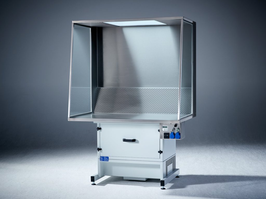 Absaugtisch von Böcker Filtertechnik mit Edelstahl-Arbeitsraum, Glasseitenwänden und hellgrauem Unterbau vor grauem Hintergrund