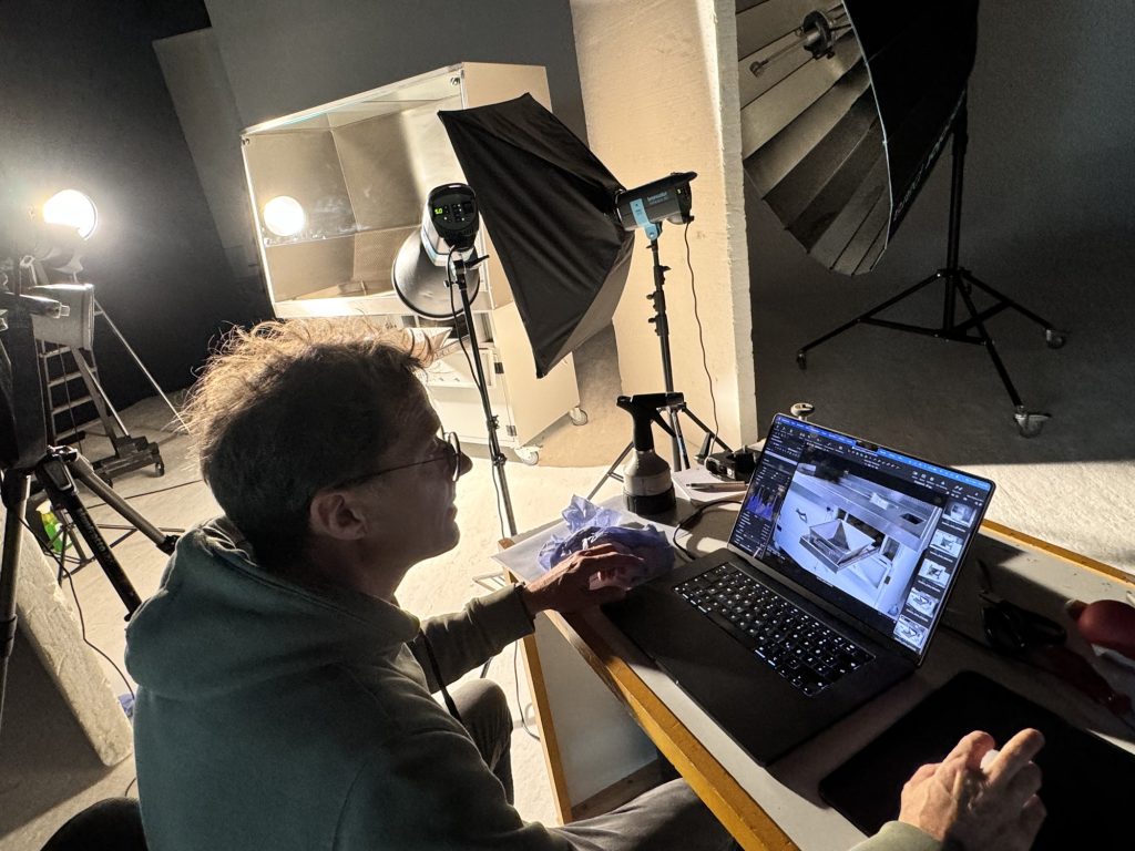 Fotograf kontrolliert die Aufnahmen des Absaugtisches am Laptop, im Hintergrund Blitze und Softbox