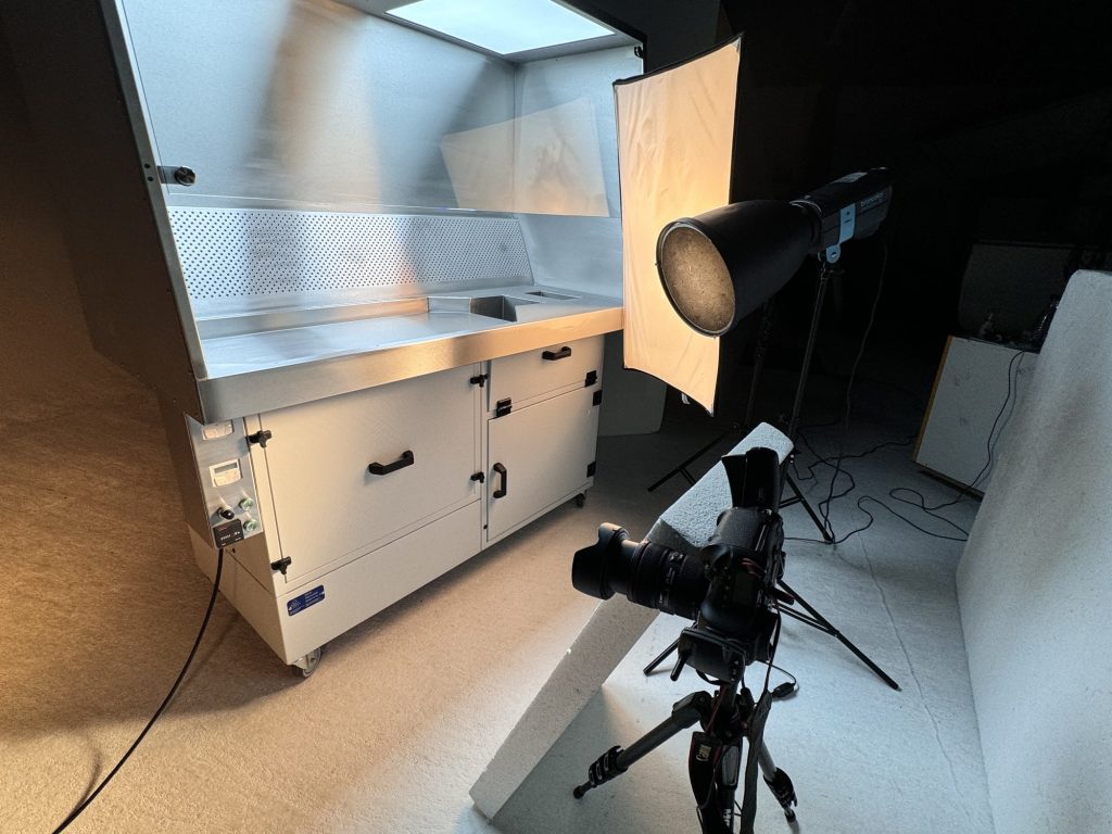Weitwinkelaufnahme des Studiosets mit Absaugtisch, Blitzlampen, Kamera auf Stativ und Styroporplatten